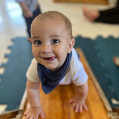 Bebê sorrindo, engatinhando em um tapete no ambiente preparado