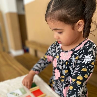 Menina concentrada explorando um material Montessori sobre a mesa